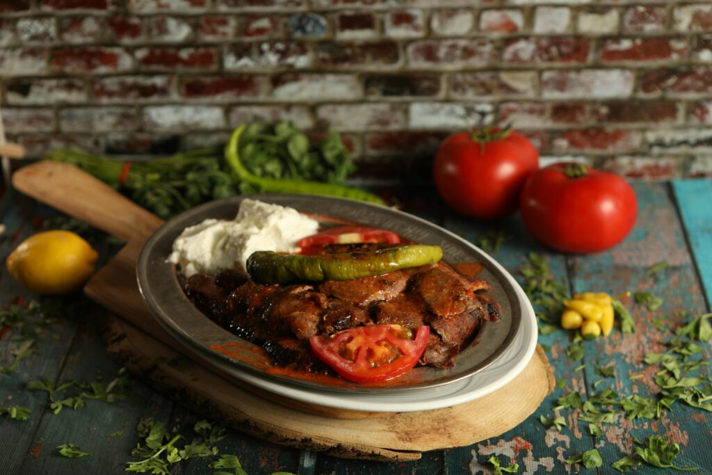 Delicious Iskender kebab served with vegetables on a rustic table setting, perfect for food lovers.